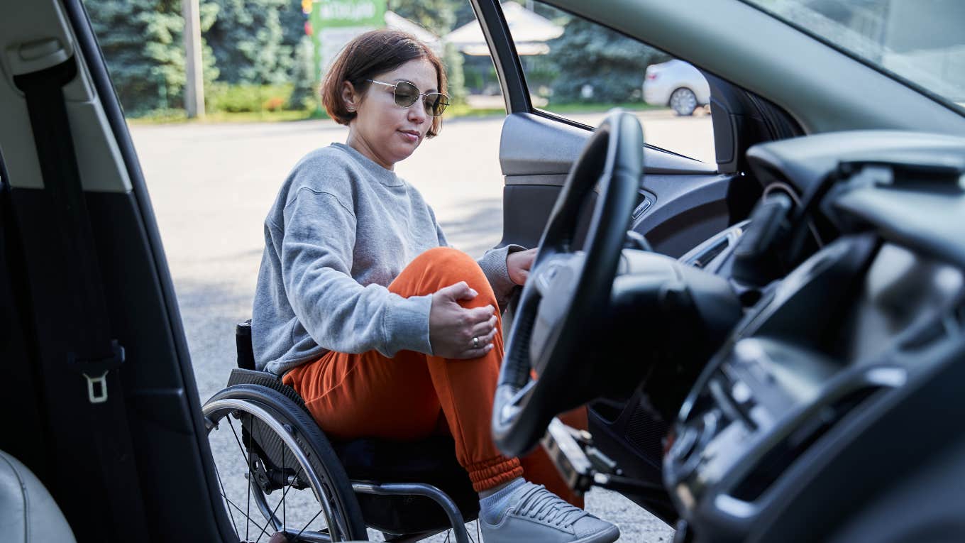 Woman Told She Looks Too Young To Be Disabled By Man Who Confronted Her For Parking In Handicapped Spot Woman opening door of her car and getting inside from sitting on wheelchair