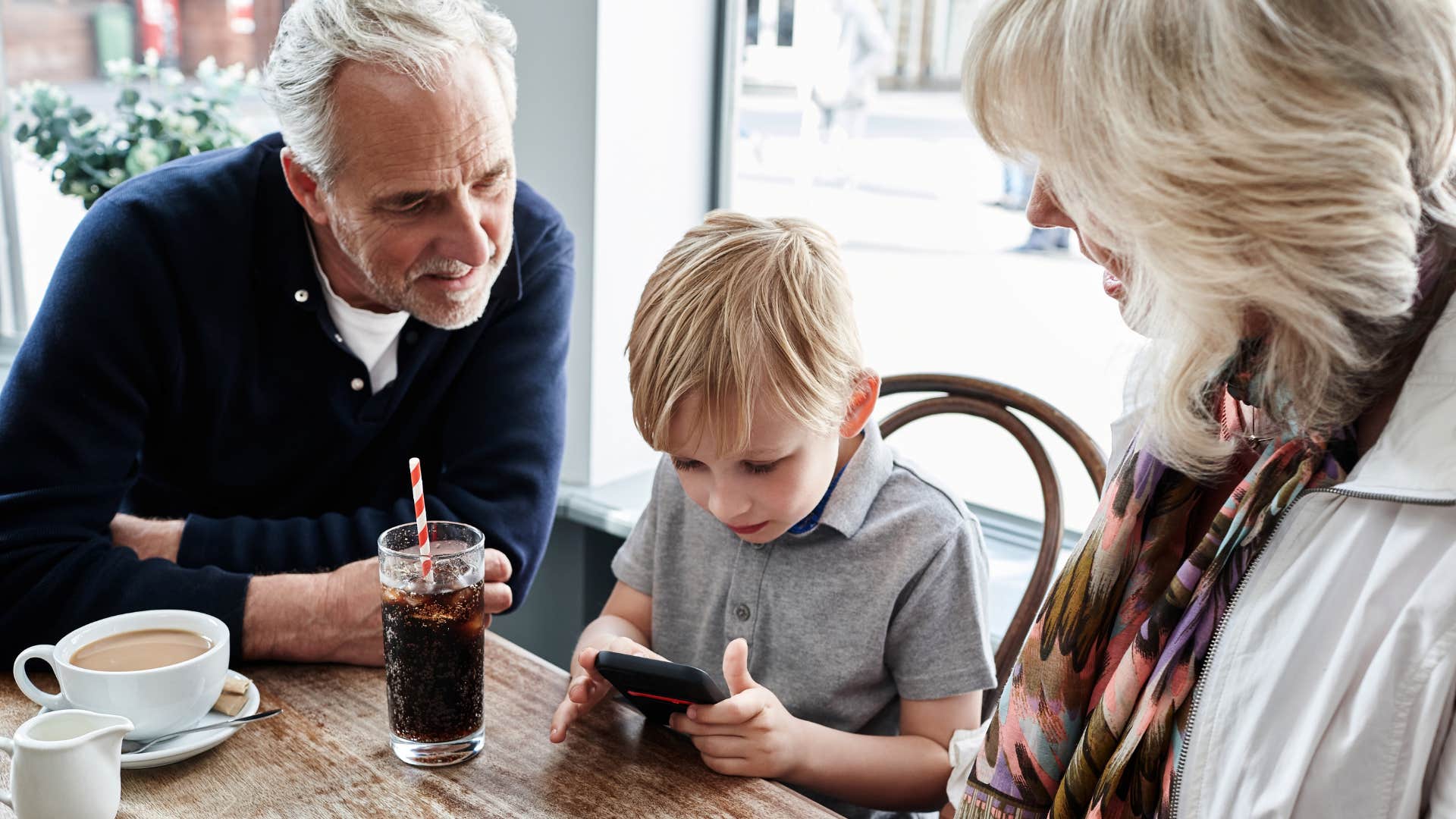 grandparents and young boy looking at a QR code at restaurant