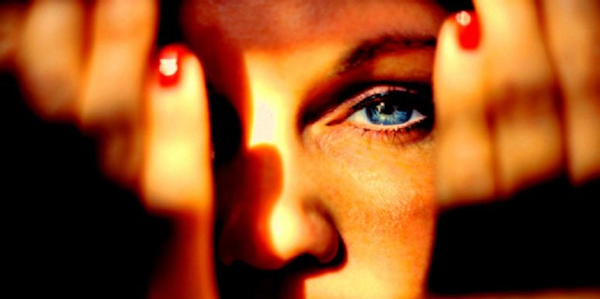 What Emotionally Unavailable Means & Signs To Look For woman with hands in front of face showing her eye