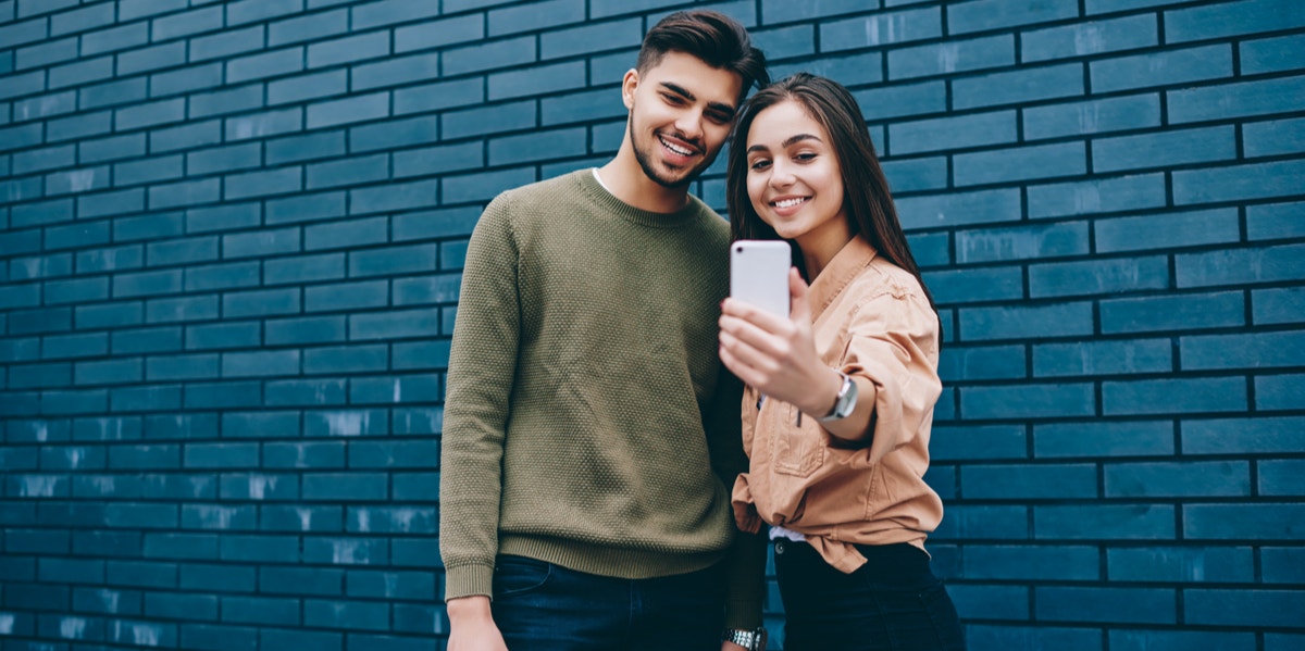 What Your Social Media Habits Weirdly Reveal About Your Relationship couple taking selfie