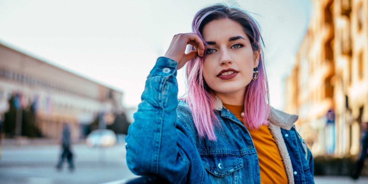 Why Knowing Exactly What You Want In Life Isn't A Bad Thing woman with pink hair smiling with hand on head